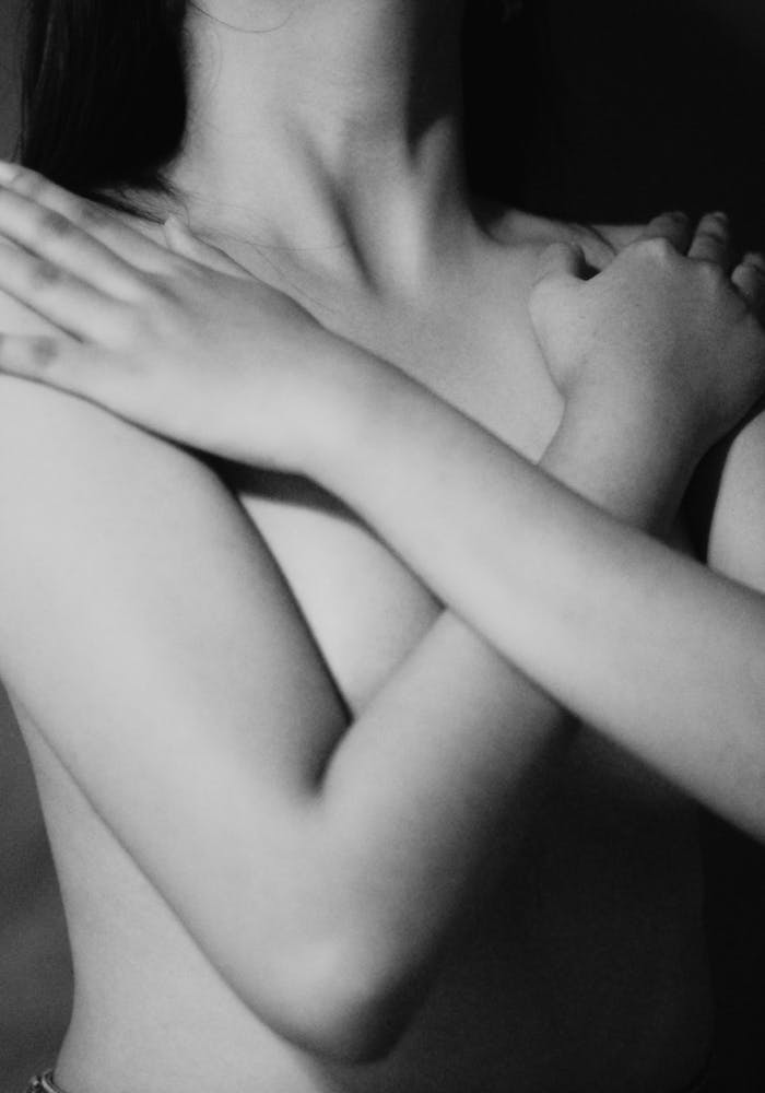 Elegant black and white close-up of a woman embracing her torso.